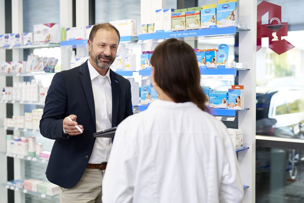Vertriebsmitarbeiter von HARTMANN im Gespräch mit einer Apothekerin zur Beratung über Medizin- und Pflegeprodukte.