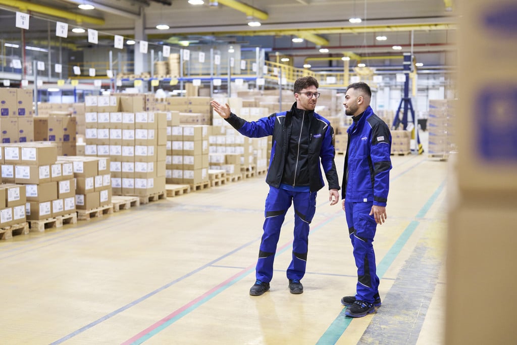 Supply Chain Manager von HARTMANN bespricht mit einem Kollegen im Lager logistische Abläufe.